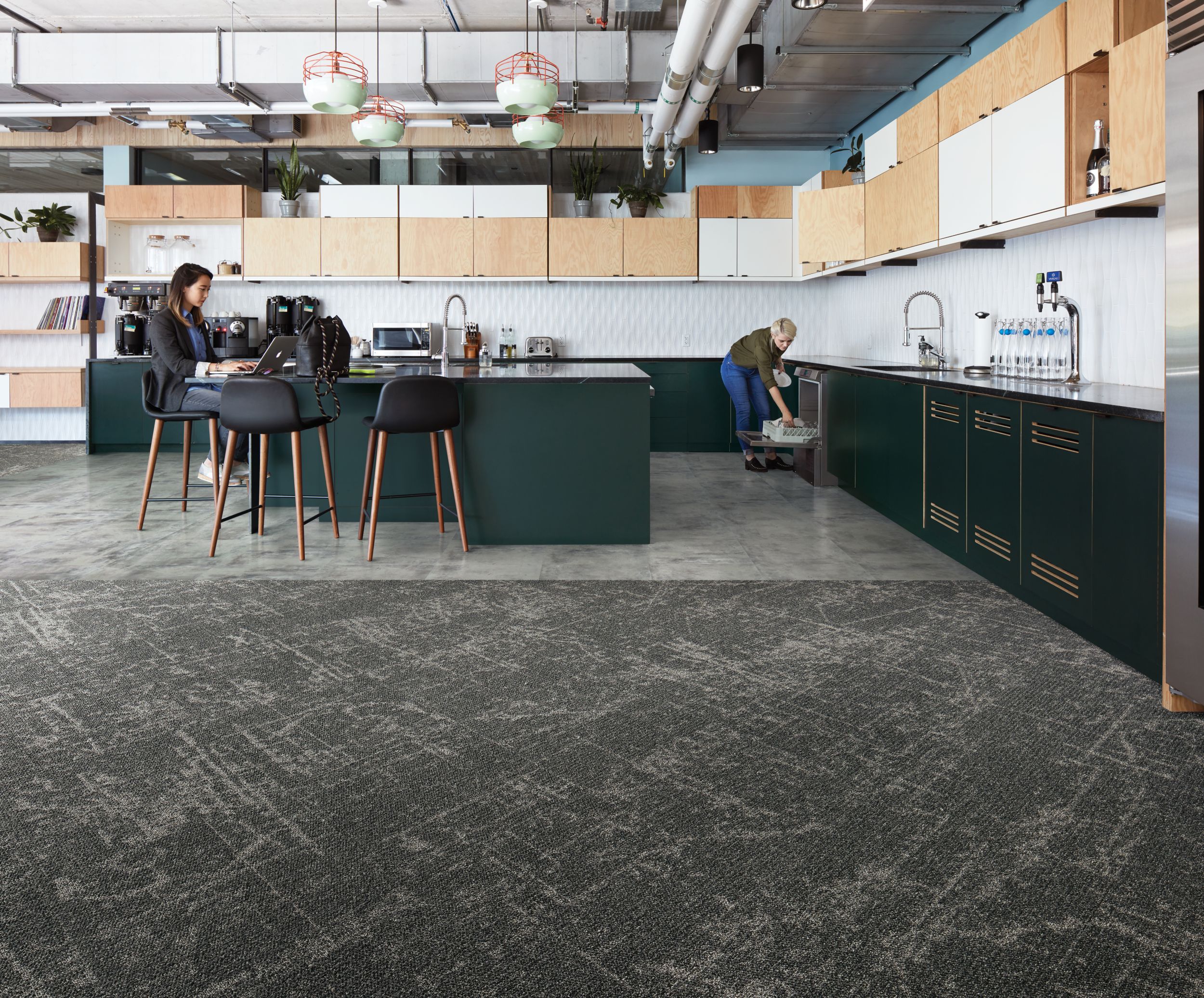 Interface Ice Breaker carpet tile and Textured Stones LVT in kitchen area with women lodaing dish washer and women working on computer image number 2